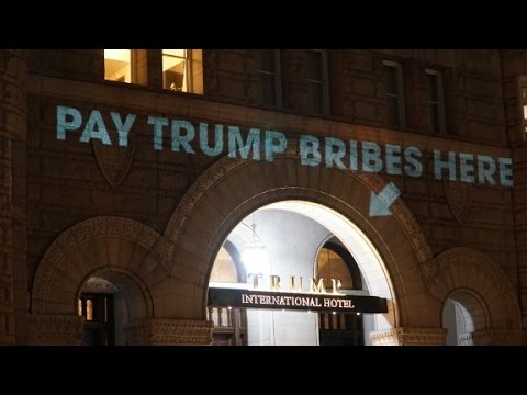pay bribes here sign projected onto trump