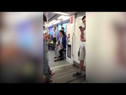 elderly woman sits on mans lap on the subway